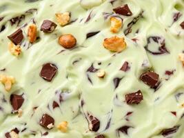 A green and brown ice cream with nuts on top photo