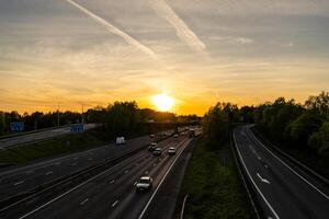 Cars driving on highway at sunset with contrails in the sky photo
