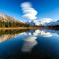 Lenticular clouds hovering over snowy mountain range reflecting in a lake photo