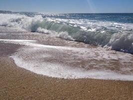 serene beach at midday with gentle waves lapping the shore and clear blue skies inviting relaxation photo