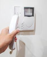 Hand holding intercom phone, security concept. Calling for assistance, receiving visitors. Use for home safety, building access, communication themes. photo