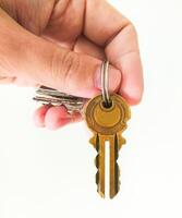 Hand holding keys, isolated on white. Symbol of opportunity, security, access, and new beginnings. Ideal for real estate, rentals, or personal growth. photo