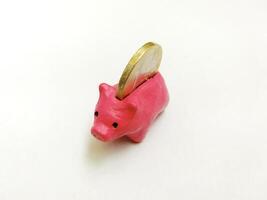 Charming pink piggy bank with a coin. Conceptual image representing savings, finance, and investment. Ideal for illustrating economic topics. White backdrop. photo