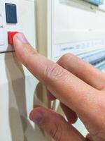 Finger presses a red button on a control panel. Concept of action, control, start, or emergency. Use for technology, industry, power, safety related themes. photo