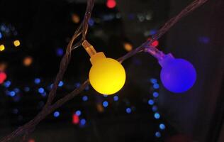 Close-up of vibrant yellow and blue LED lights on a string, creating a festive and modern bokeh effect against a dark background. photo