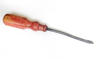 A weathered, vintage screwdriver with a worn, reddishbrown handle rests against a stark white background. photo