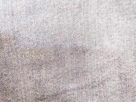 Detailed texture of worn blue denim fabric. Ideal for backgrounds, apparel design, or representing comfort and durability. Versatile and visually appealing. photo