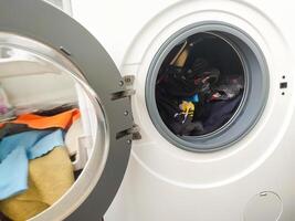 Open washing machine filled with colorful clothes. Laundry day concept. Cleaning, household chores, and routine. Use for lifestyle, home, or hygiene topics. photo