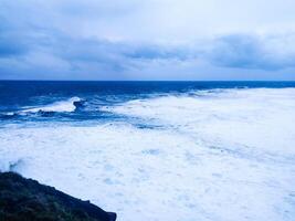 Dramatic ocean landscape featuring turbulent waves under a moody sky. Evokes themes of power, nature, and unpredictability. Ideal for conveying strength and resilience. photo