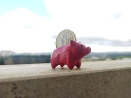 A pink piggy bank with a euro coin stands on ledge, representing savings, finance, and economic growth. Ideal for illustrating investment, budget planning, or future wealth. photo
