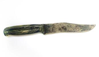 A weathered, vintage knife with a dark green, textured handle rests against a stark white backdrop. The blade shows signs of age and use, adding character and a sense of history. photo