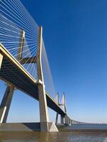 Stunning lowangle view of a modern cablestayed bridge against a vibrant blue sky. photo