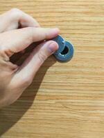 Hand opening peephole cover on a wood door, closeup. Represents privacy, security, and anticipation. Use for home safety, access control, and property themes. photo