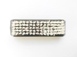 Overhead shot of a rectangular brush with stiff, offwhite bristles against a clean white background. Perfect for illustrating cleaning, organization, or even the concept of scrubbing away problems. photo