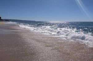 A serene beach at with gentle waves lapping the shore and clear blue inviting relaxation photo
