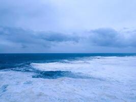 Dramatic seascape featuring turbulent waves under a moody, overcast sky. Evokes raw power, isolation, and the beauty of nature. Perfect for weather, travel, or environmental concepts. photo