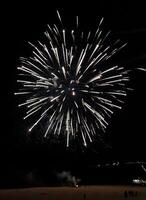 Stunning fireworks display exploding in a vibrant burst of white against a dark night sky. Perfect for celebratory themes, backgrounds, and holiday content. photo