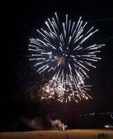 Stunning fireworks display illuminating the night sky. Bright, radiant bursts create a captivating spectacle perfect for celebrations, holiday promotions, or event coverage. photo