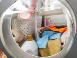 Household cleaning supplies and laundry items organized within a clear storage unit. Concept for organization, chores, home keeping, and efficient space utilization. photo