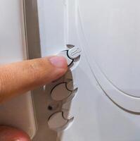 Closeup shot focusing on a finger adjusting settings or controls on a white device. Symbol of precision, technology, or domestic appliances. Usable for service or assistance concepts. photo