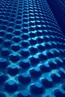 Rows Of Circle Extruded Parts On Cylindrical Structure. Abstract 3D Background With Blue Elements On Rolled Surface photo