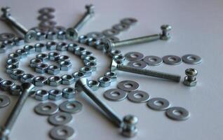 Nuts, Washers And Bolts Arranged In Star Pattern On White Surface Angle View photo