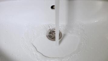 stream of water flows from the tap into the white sink video