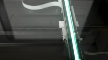 The scanning head of an office scanner moves smoothly beneath the glass surface, illuminating the document as it captures every detail during the scanning process. video