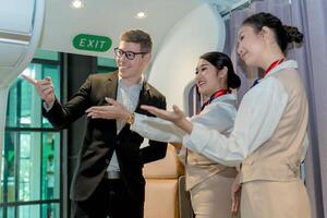 Friendly flight attendants guiding a smiling business traveler during airplane boarding near the exit, showing direction with welcoming gestures photo