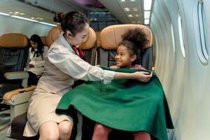 Flight attendant caring for a smiling child by wrapping her in a blanket during flight, showcasing airline comfort, safety, and exceptional in-flight service photo