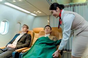 Flight attendant offering blanket to resting business class passenger during flight, highlighting care, comfort, and premium in-flight service experience photo