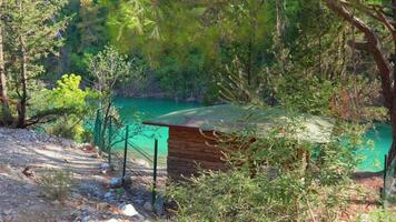 Cabin by turquoise lake in forest landscape video