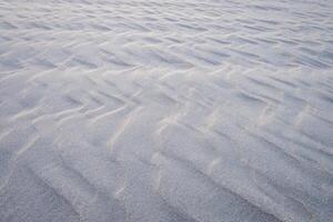 Smooth sand ripples creating a natural abstract texture, perfect as a serene, minimalistic background for creative designs photo