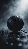 a black sphere with water droplets on its surface, taken from a low angle with a shallow depth of field photo