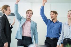 Team celebrates successful presentation in modern office setting during afternoon meeting with enthusiastic gestures photo