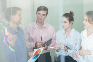 Team members collaborate in a modern office during a strategy meeting while analyzing data on charts and reports photo