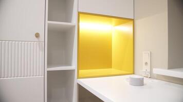 Modern white cabinet with illuminated yellow shelf and countertop video
