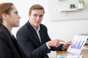 Business professional presents data analysis to a colleague during an office meeting in a modern workspace photo