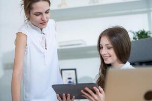 Colleagues discussing project details on a tablet in a modern office setting during the day photo