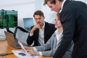 Business professionals discussing data analysis in a modern office environment with charts and computers in view photo