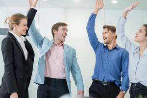 Team celebrates success in modern office setting with enthusiastic gestures and bright expressions during a collaborative meeting photo