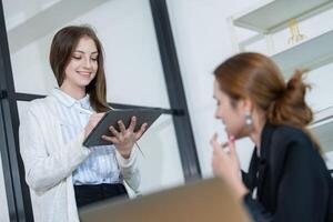 Young professional engages in a collaborative meeting while using a tablet in a modern office setting photo