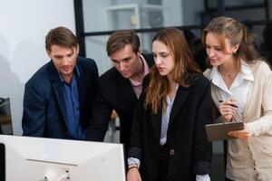 Team collaborates on project while reviewing data on computer screen in a modern office setting photo