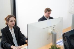 Professional young adults working focused on their computers in a modern office setting during the day photo
