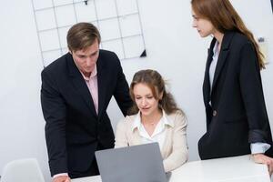 Team collaboration during a business meeting in a modern office setting with focus on a laptop photo