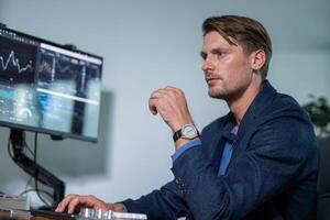 Professional man analyzing financial data in a modern office setting with multiple screens during daytime hours photo