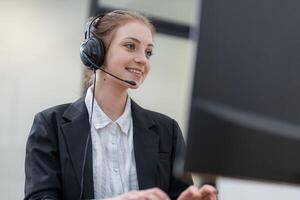 Young woman engaging in customer support while using a headset at her desk in a modern office environment photo