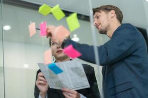 Collaborative brainstorming session in modern office with sticky notes on glass wall photo