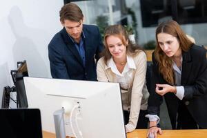 Professionals collaborating in modern office, analyzing data on computer screen, emphasizing teamwork and innovation photo