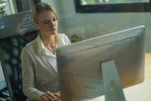 Professional woman working at a computer in a modern office environment during the day photo